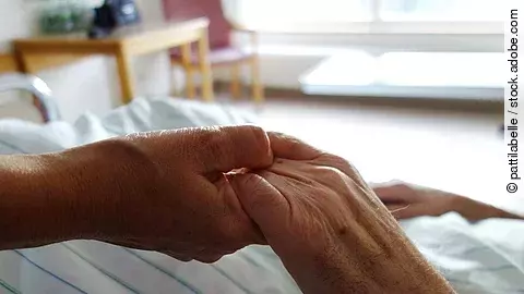 Pflege Zwei Hände, die sich auf einem weißen Bettlaken halten