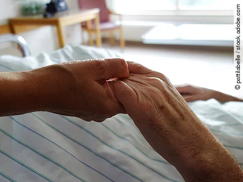 Zwei Hände, die sich auf einem weißen Bettlaken halten