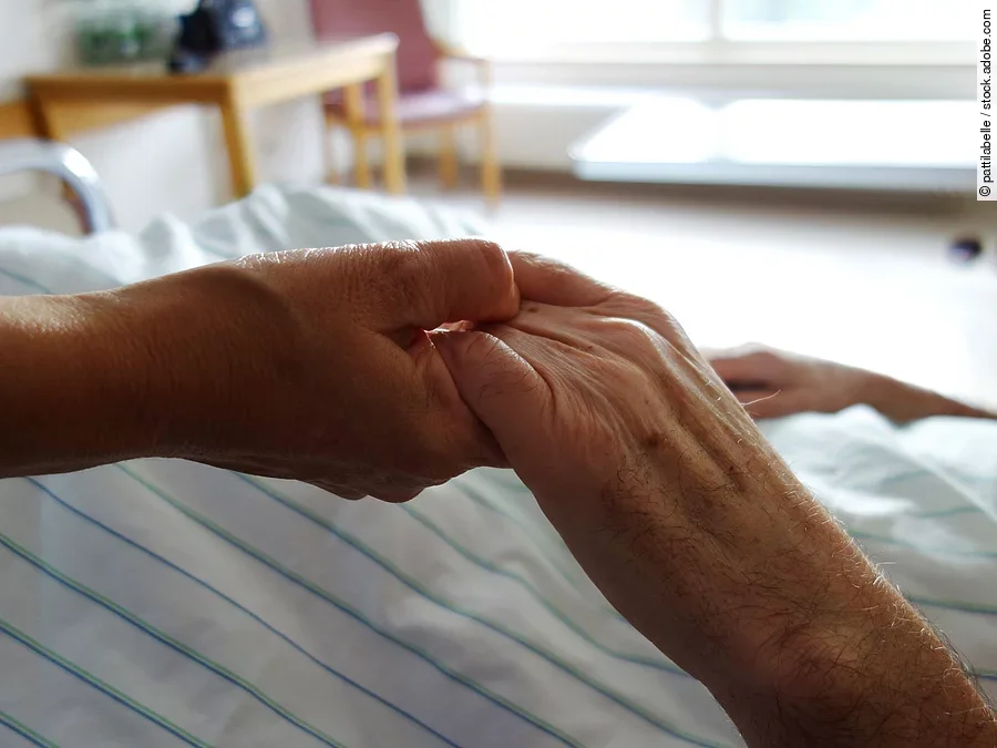 Zwei Hände, die sich auf einem weißen Bettlaken halten