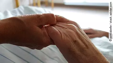 Pflege Zwei Hände, die sich auf einem weißen Bettlaken halten