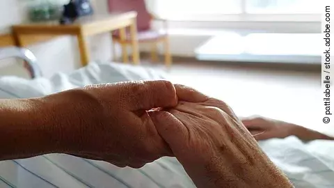 Zwei Hände, die sich auf einem weißen Bettlaken halten