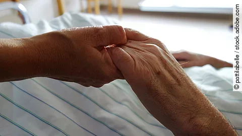 Pflege Zwei Hände, die sich auf einem weißen Bettlaken halten