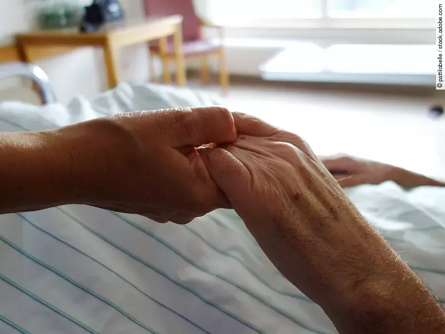 Zwei Hände, die sich auf einem weißen Bettlaken halten