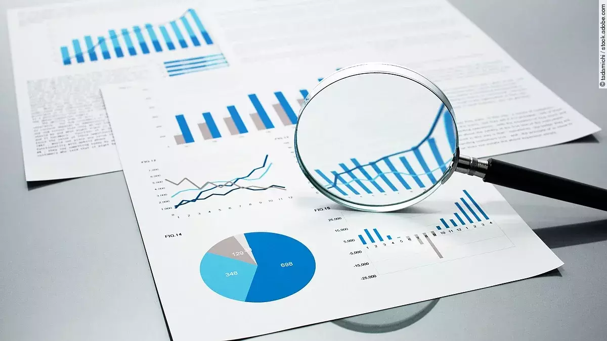 Gutachten Eine Lupe, die auf Diagramme und Statistiken gerichtet ist