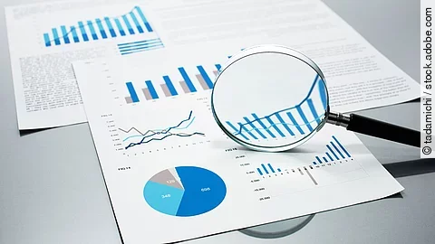 Gutachten Eine Lupe, die auf Diagramme und Statistiken gerichtet ist