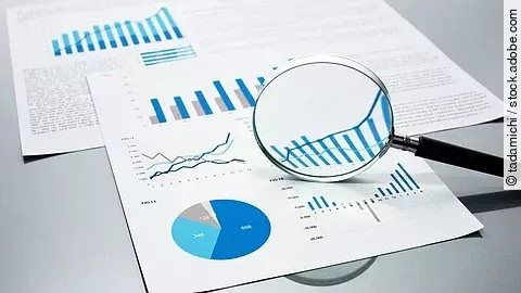 Eine Lupe, die auf Diagramme und Statistiken gerichtet ist