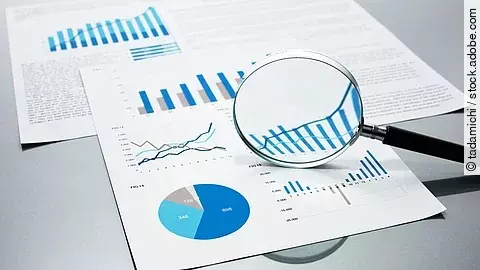 Eine Lupe, die auf Diagramme und Statistiken gerichtet ist