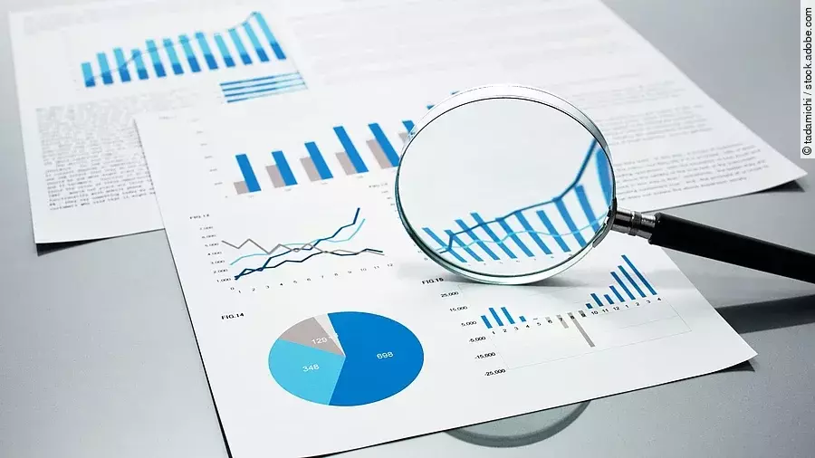 Eine Lupe, die auf Diagramme und Statistiken gerichtet ist