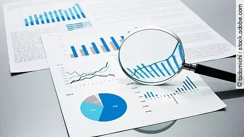 Gutachten Eine Lupe, die auf Diagramme und Statistiken gerichtet ist