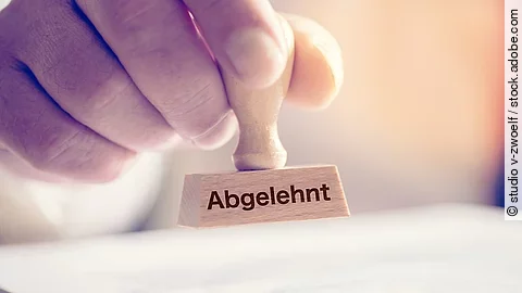 Eine Hand hält einen Stempel mit dem Aufdruck Abgelehnt