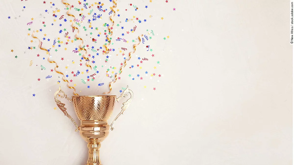 Award Eine Trophähe aus Gold, aus der Konfetti kommt.