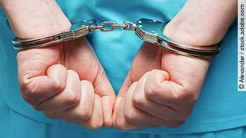 Ein Arzt trägt Handschellen.