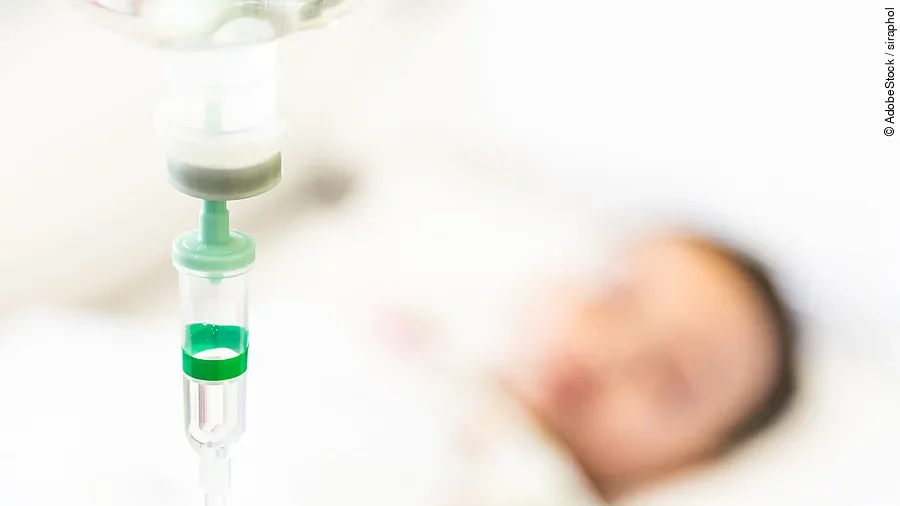 Patient mit Infusion Eine Infusion, im Hintergrund ist verschwommen ein Patient zu sehen