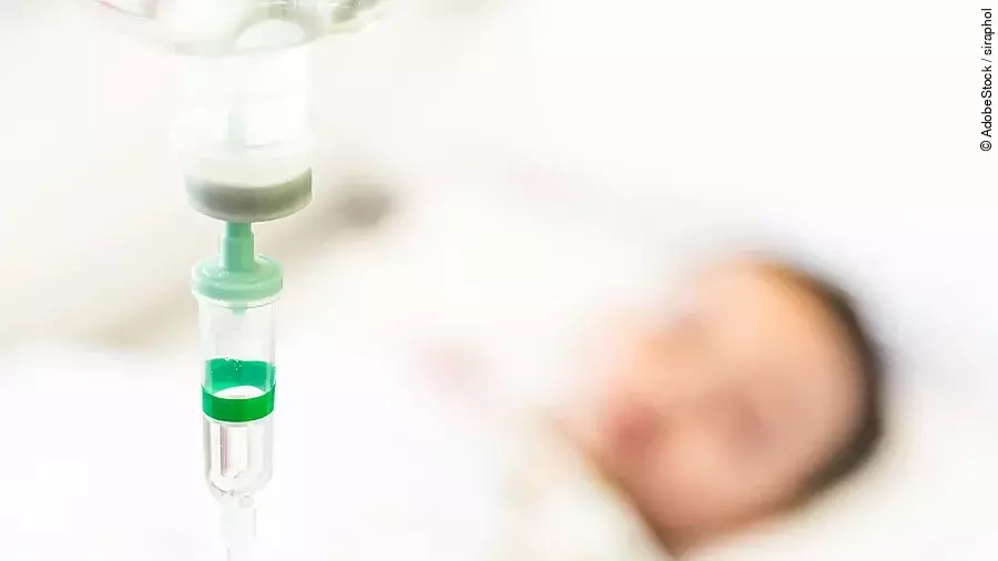 Eine Infusion, im Hintergrund ist verschwommen ein Patient zu sehen