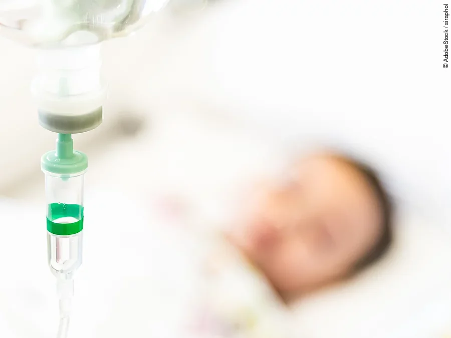 Patient mit Infusion Eine Infusion, im Hintergrund ist verschwommen ein Patient zu sehen