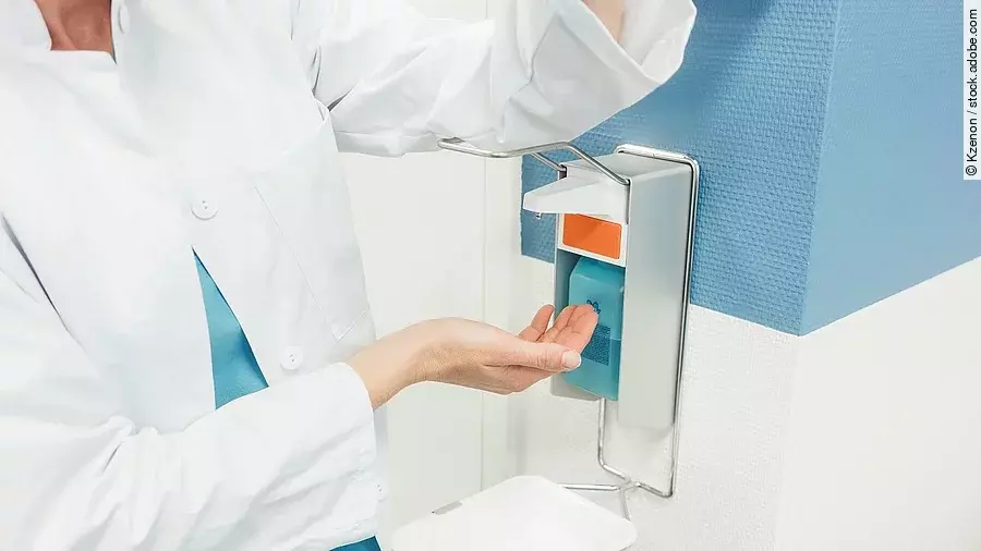 Desinfektion Ein Arzt betätigt mit dem Ellenbogen einen Desinfektionsspender im Krankenhaus.