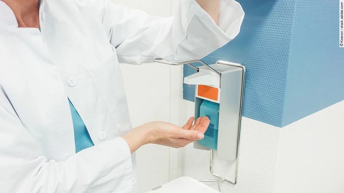 Desinfektion Ein Arzt betätigt mit dem Ellenbogen einen Desinfektionsspender im Krankenhaus.
