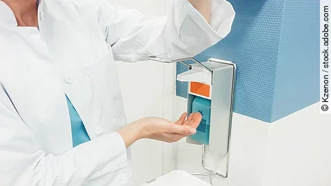 Ein Arzt betätigt mit dem Ellenbogen einen Desinfektionsspender im Krankenhaus.