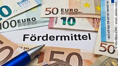 Euro-Scheine umgeben einen Zettel mit der Aufschrift "Fördermittel"