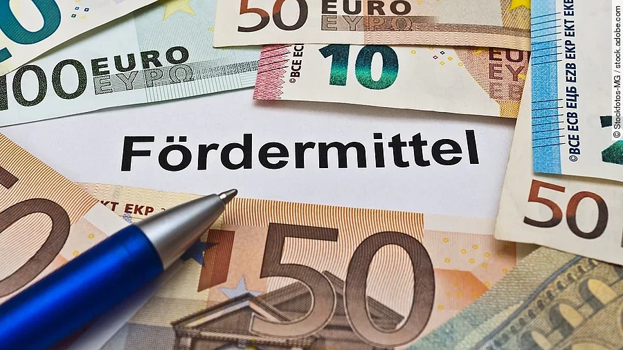 Euro-Scheine umgeben einen Zettel mit der Aufschrift "Fördermittel"