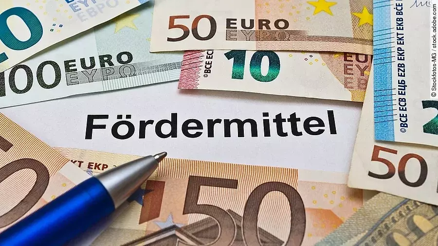 Euro-Scheine umgeben einen Zettel mit der Aufschrift "Fördermittel"