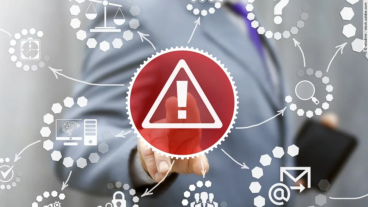 Von einem roten Dreieck mit Ausrufezeichen gehen weitere weiße Symbole aus: ein Fragezeichen, eine Lupe, ein Brief mit @-Zeichen, eine Waage und mehr. Im Hintergrund ist ein Geschäftsmann im Anzug zu sehen.