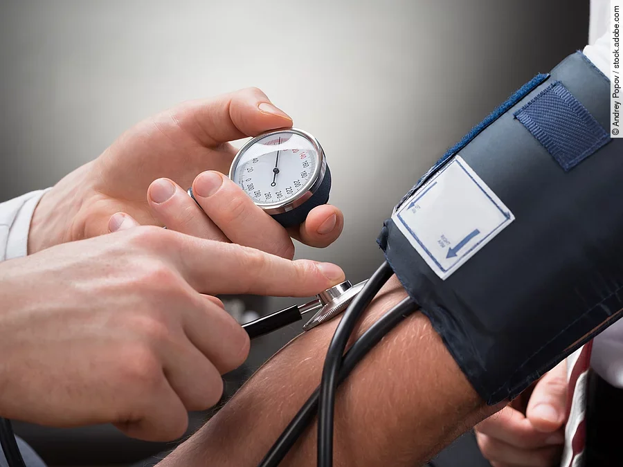 Eine Person misst den Blutdruck einer anderen Person mittels Oberarm-Blutdruckmessgerät.