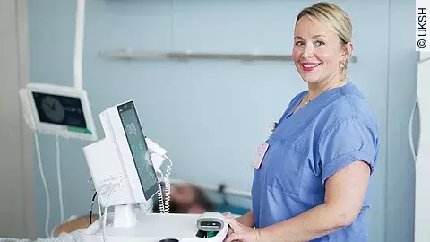 Pflegefachkraft steht am Monitor