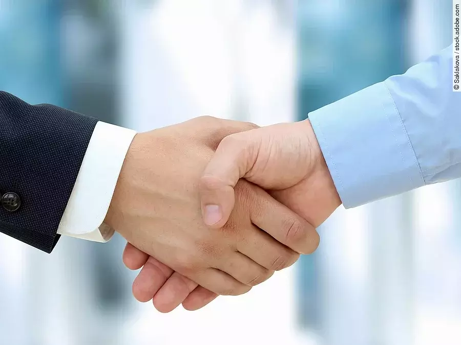 Eine Person im Anzug und eine Person im Hemd schlagen Hände ein.