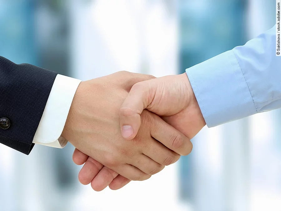 Eine Person im Anzug und eine Person im Hemd schlagen Hände ein.