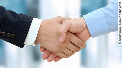 Eine Person im Anzug und eine Person im Hemd schlagen Hände ein.