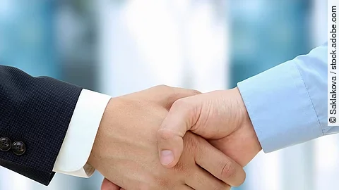 Eine Person im Anzug und eine Person im Hemd schlagen Hände ein.