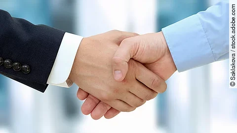 Eine Person im Anzug und eine Person im Hemd schlagen Hände ein.