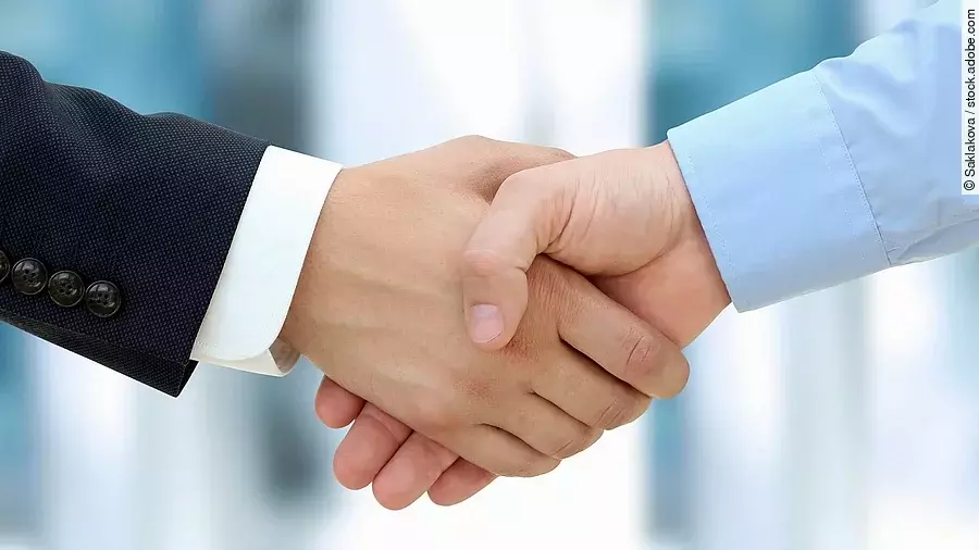 Eine Person im Anzug und eine Person im Hemd schlagen Hände ein.