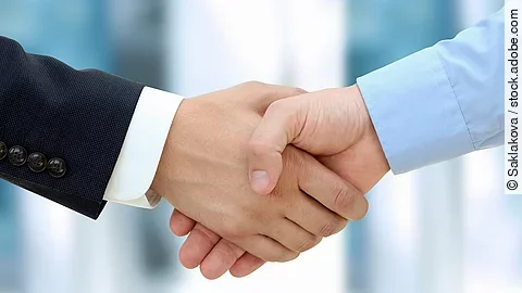 Handschlag Eine Person im Anzug und eine Person im Hemd schlagen Hände ein.