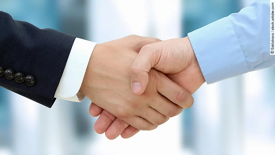 Eine Person im Anzug und eine Person im Hemd schlagen Hände ein.