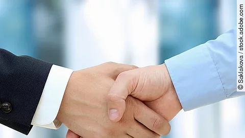 Eine Person im Anzug und eine Person im Hemd schlagen Hände ein.