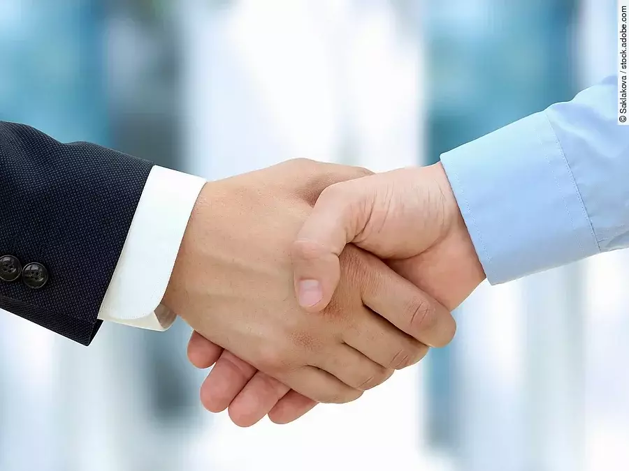 Eine Person im Anzug und eine Person im Hemd schlagen Hände ein.