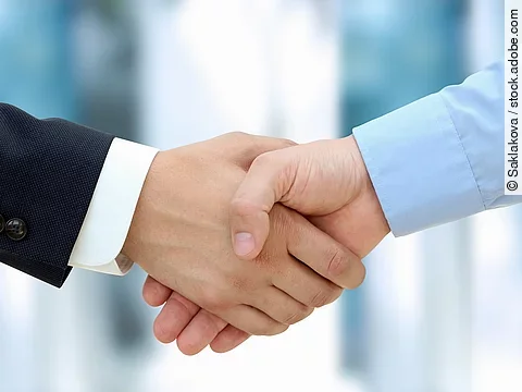 Eine Person im Anzug und eine Person im Hemd schlagen Hände ein.