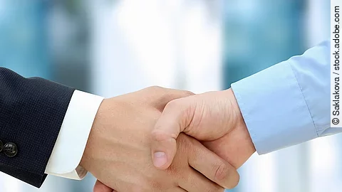 Eine Person im Anzug und eine Person im Hemd schlagen Hände ein.