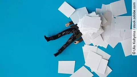 Eine Person liegt vergraben unter einem Papierstapel
