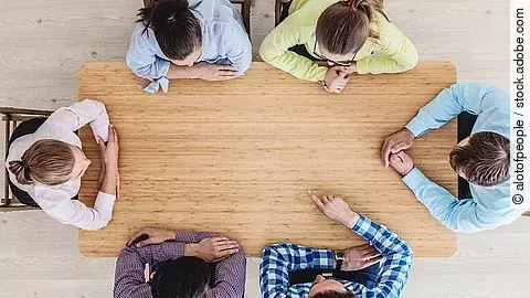 Gesprächsrunde mit sechs Personen an einem hölzernen Tisch