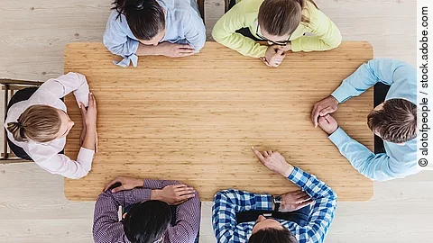 Gesprächsrunde mit sechs Personen an einem hölzernen Tisch