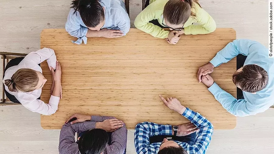 Gespräch Gesprächsrunde mit sechs Personen an einem hölzernen Tisch
