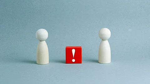 Zwei Spielfiguren stehen sich gegenüber, dazwischen ein roter Würfel mit Ausrufezeichen.