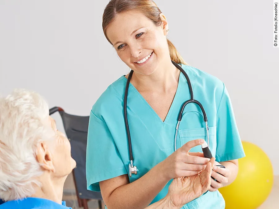 Patientin im Rollstuhl mit Krankenpflegerin