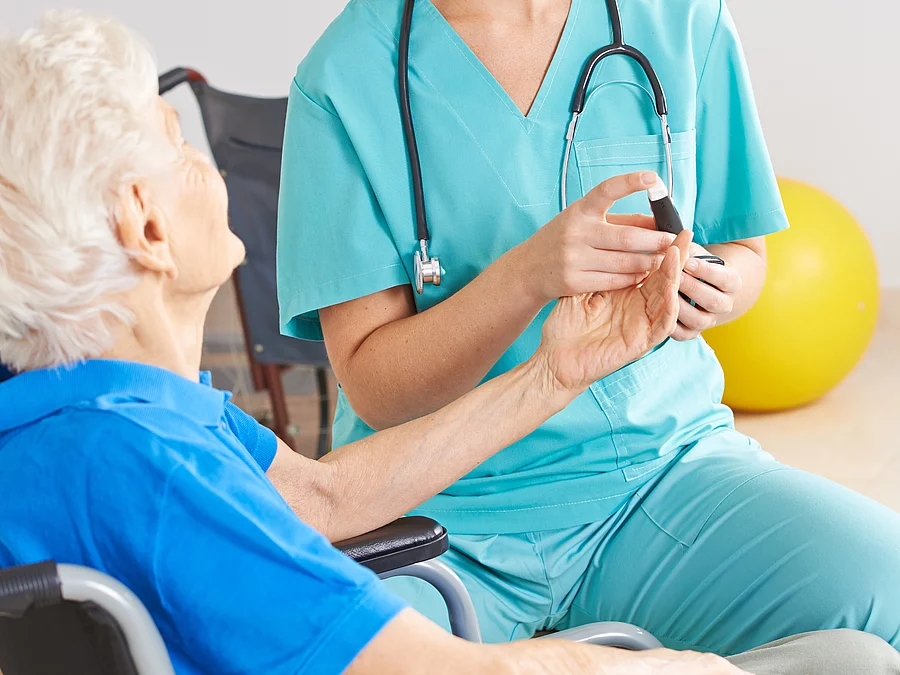 Patientin im Rollstuhl mit Krankenpflegerin