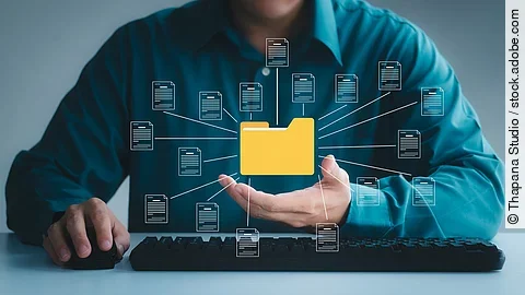 Ordner Ein gelber Ordner schwebt in der über der Hand einer Person.