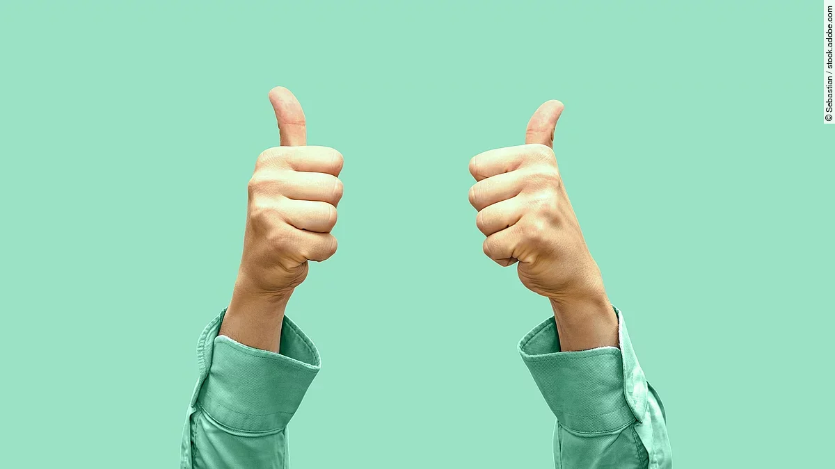 Daumen hoch Vor türkisem Hintergrund zeigen zwei Hände Daumen nach oben.