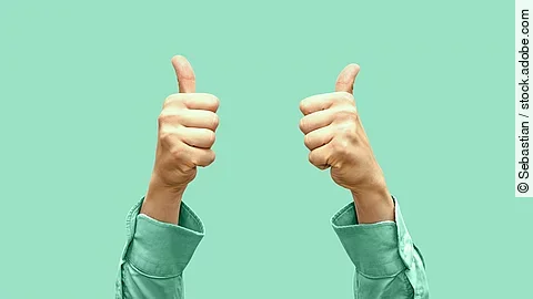 Daumen hoch Vor türkisem Hintergrund zeigen zwei Hände Daumen nach oben.